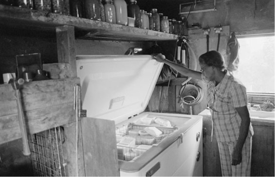 Historical photo of a women with old refrigerator & frozen food inside